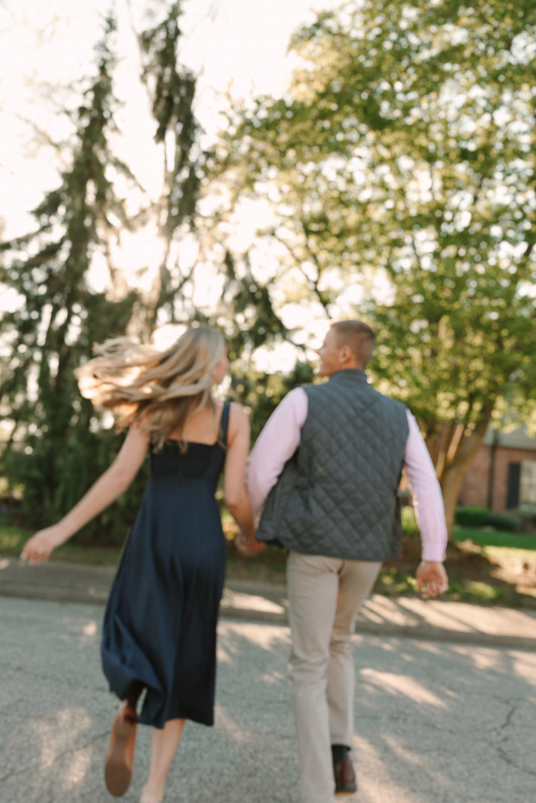 Katherine and Jackson embracing during their Evansville Indiana engagement session with golden sunlight and evergreen trees.