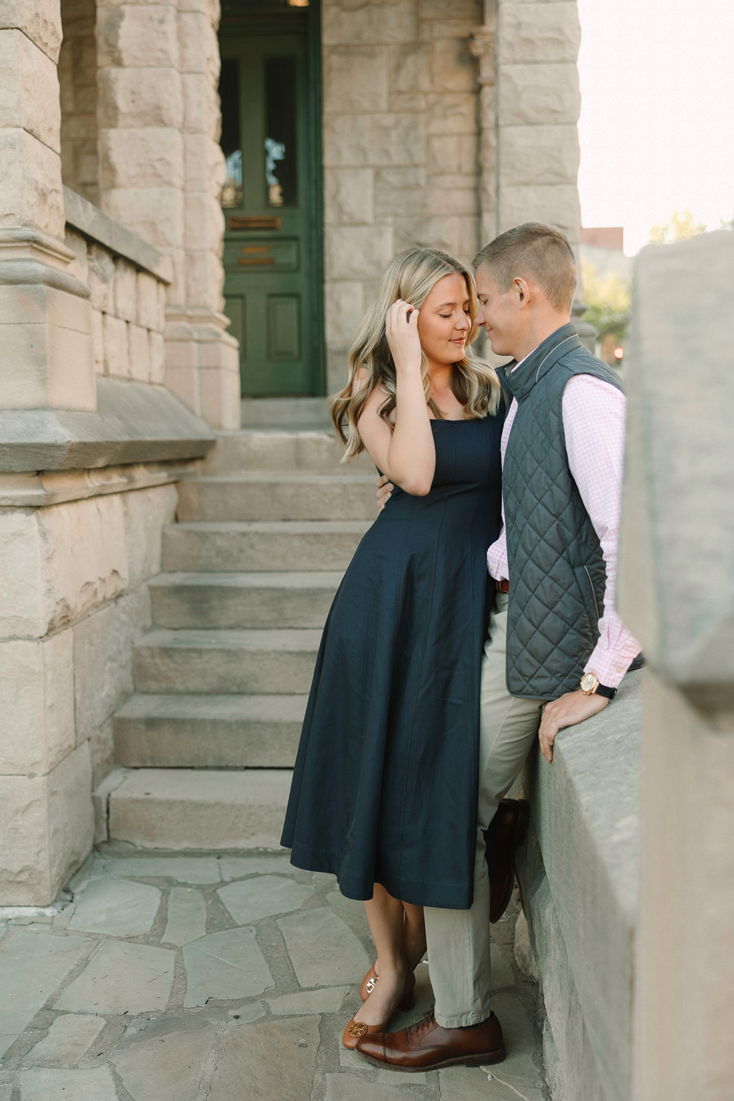 Katherine and Jackson embracing during their Evansville Indiana engagement session with golden sunlight and evergreen trees.