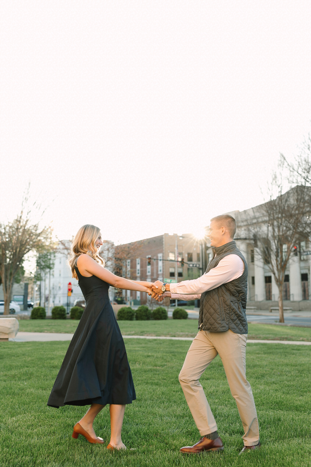 Katherine and Jackson embracing during their Evansville Indiana engagement session with golden sunlight and evergreen trees.