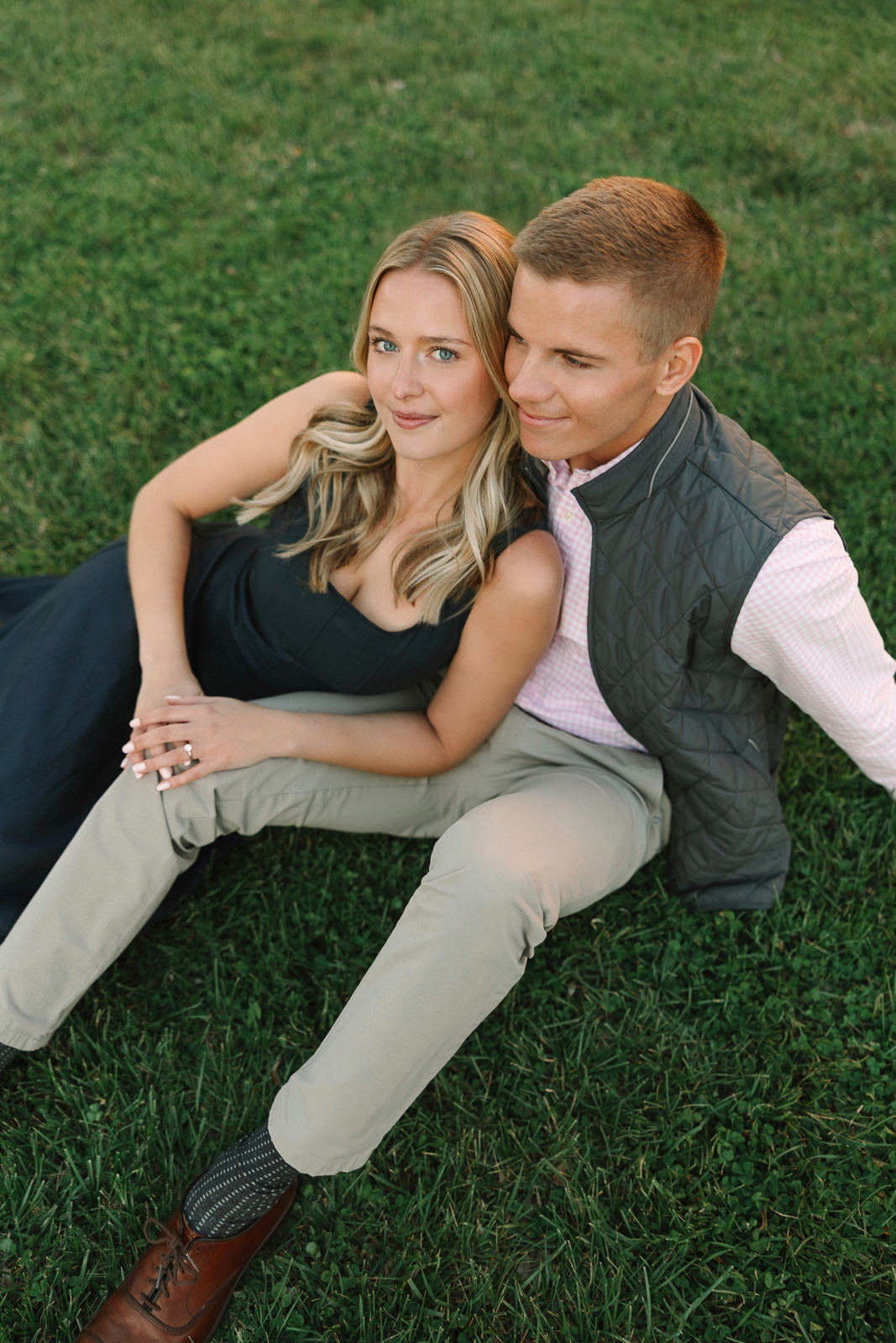 Katherine and Jackson embracing during their Evansville Indiana engagement session with golden sunlight and evergreen trees.