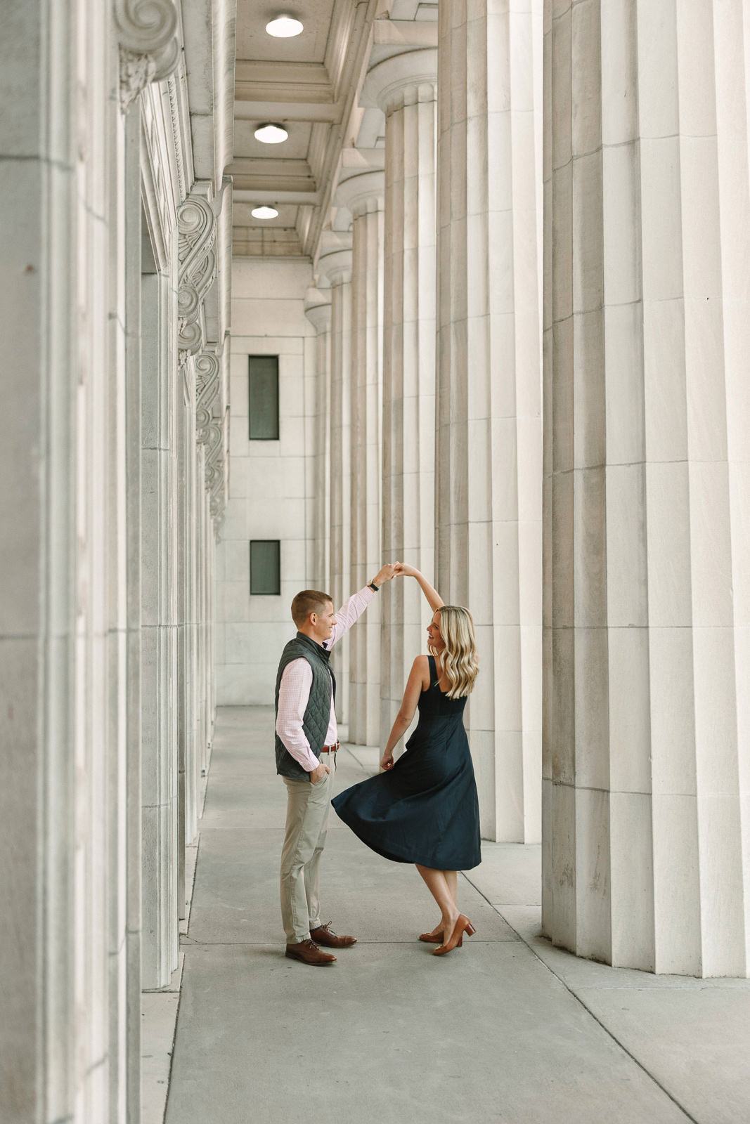 Katherine and Jackson embracing during their Evansville Indiana engagement session with golden sunlight and evergreen trees.