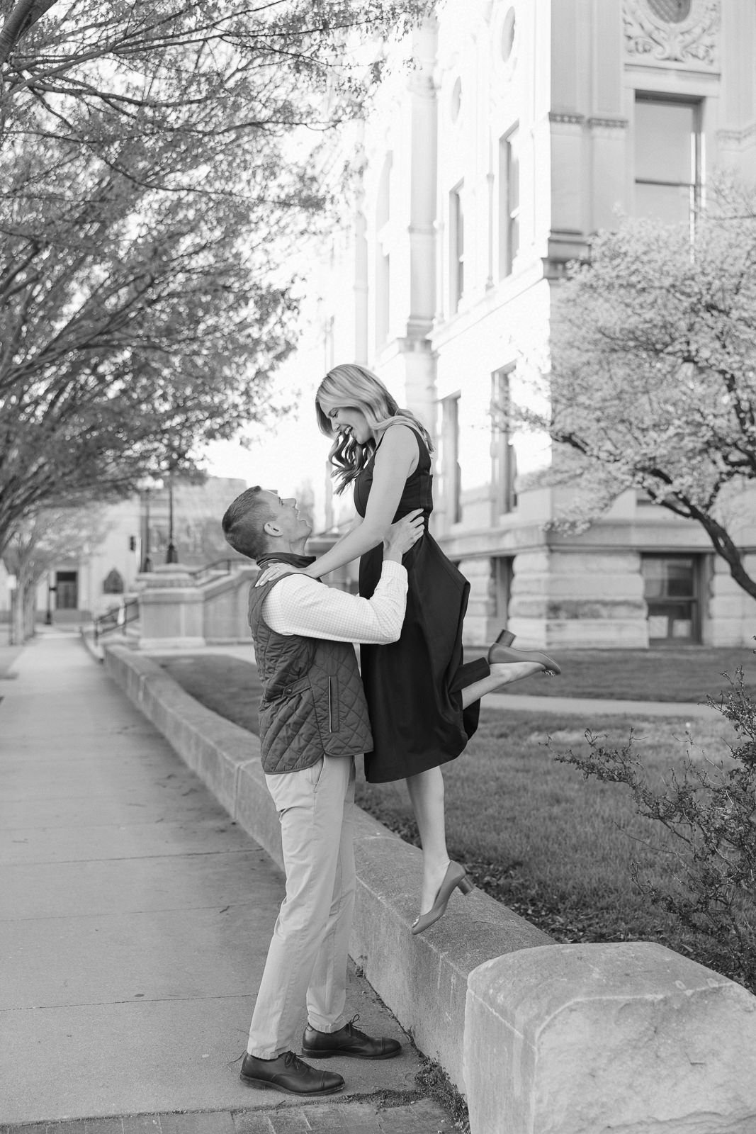 Katherine and Jackson embracing during their Evansville Indiana engagement session with golden sunlight and evergreen trees.